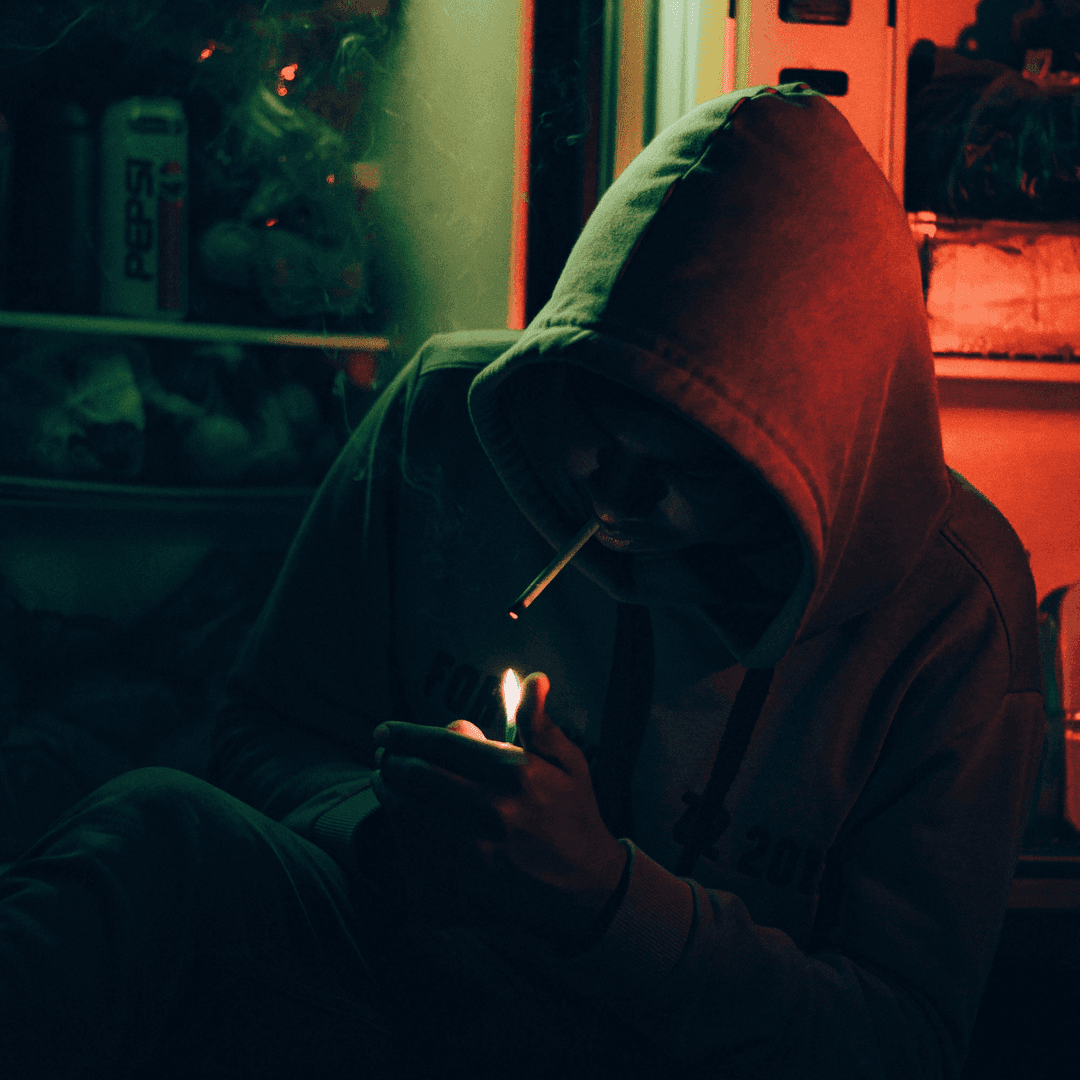 man in hoodie lighting joint
